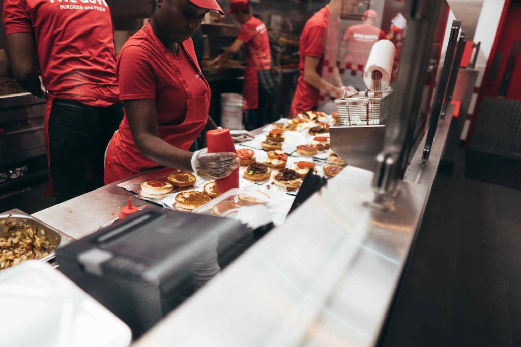 Cuisine d'un restaurant de restauration rapide. Une employée est entrain de préparer des burgers