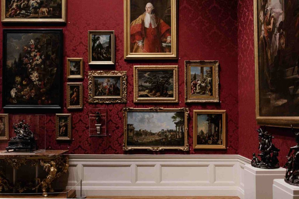 Galerie d'un musée avec un mur rouge remplie d'œuvres d'art