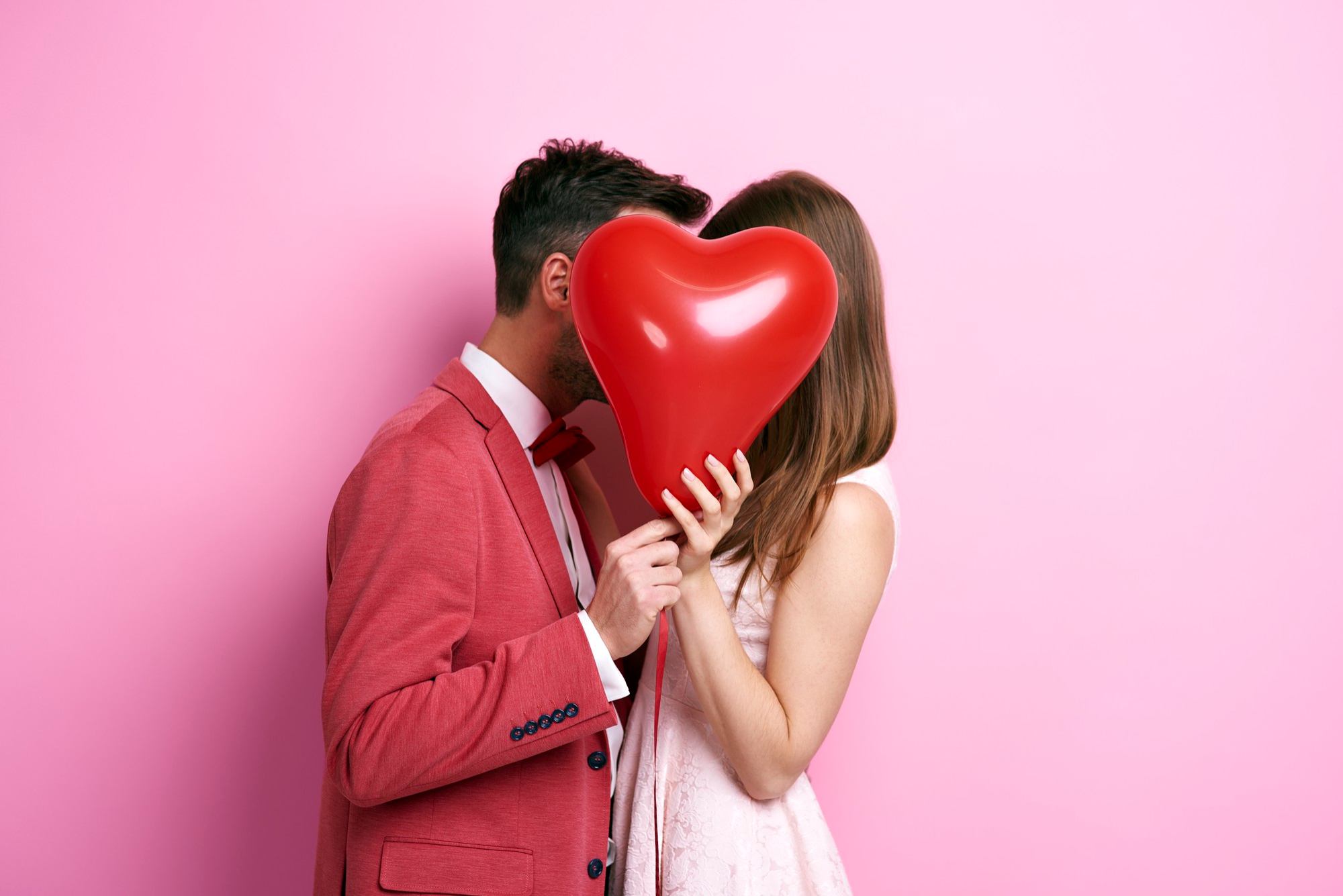 Couple s'embrassant derrière un ballon en forme de coeur