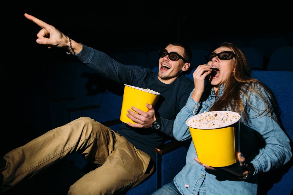 jeune couple avec popcorn regardant un film d'action au cinéma