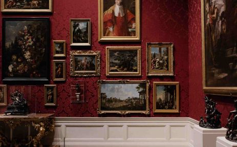 Galerie d'un musée avec un mur rouge remplie d'œuvres d'art